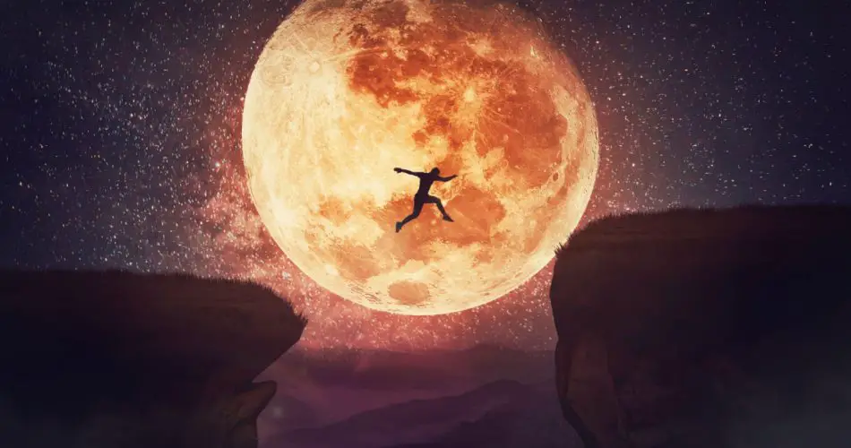 A man jumping off the cliff with moon in the background